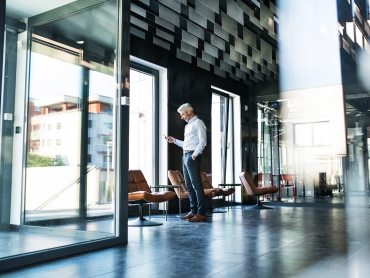 Mature-businessman-with-smartphone-in-the-office.