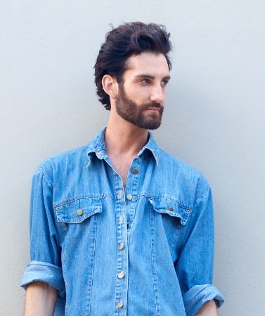 Male fashion model with beard holding a travel bag