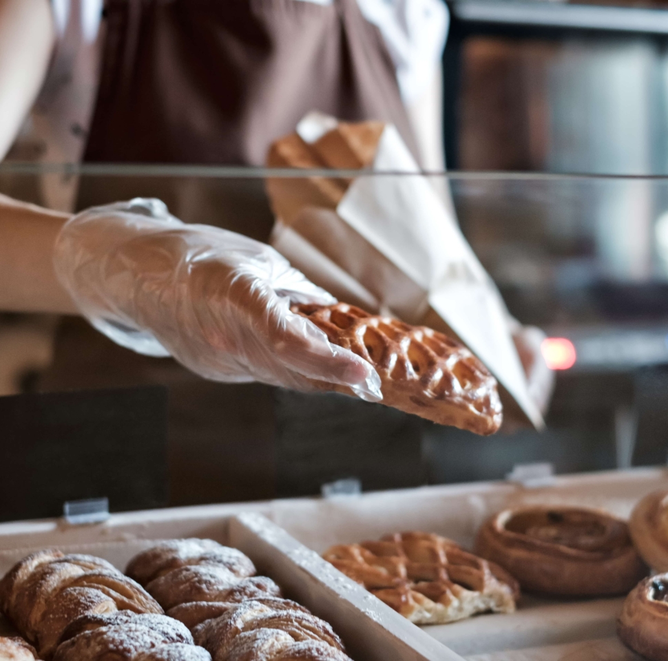 European woman sells in bakery putting bread in paper bag. Small business concept