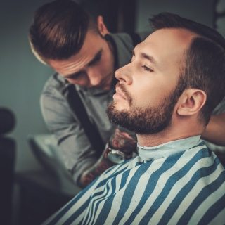 confident-man-visiting-hairstylist-in-barber-shop-PR3JT7K
