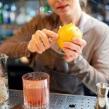 bartender-peels-orange-peel-for-cocktail-at-bar-P97775Y
