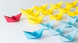 Business competition concept using two different color origami paper boats