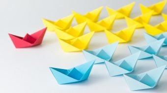 Business competition concept using two different color origami paper boats