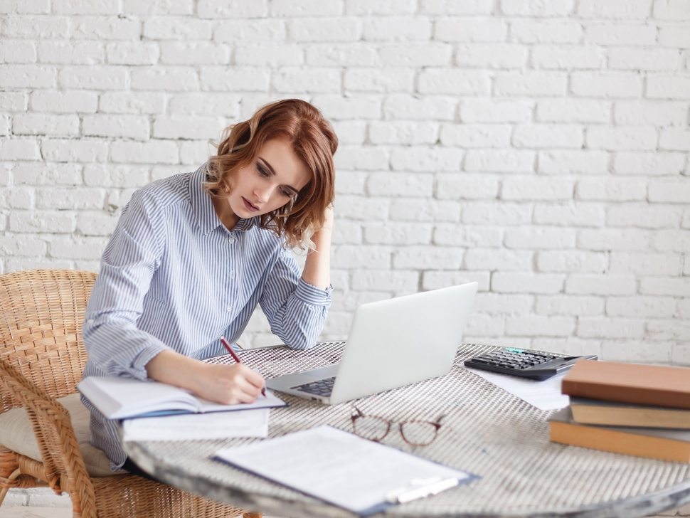 Woman freelancer female hands with pen writing on notebook at home or office.