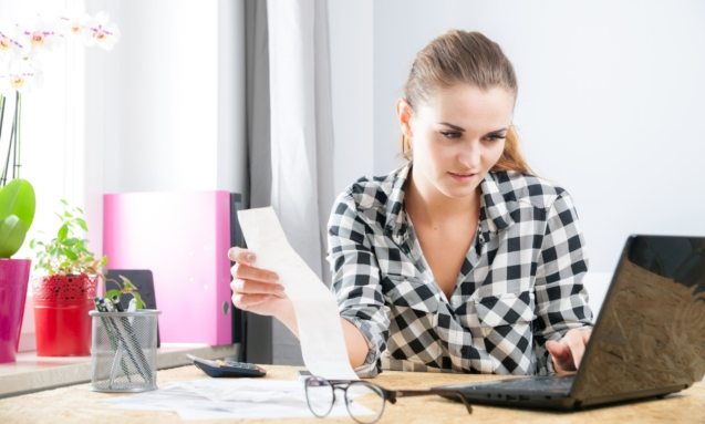 Smiling young woman calculating and paying bills in home office 4-39051-original-protected