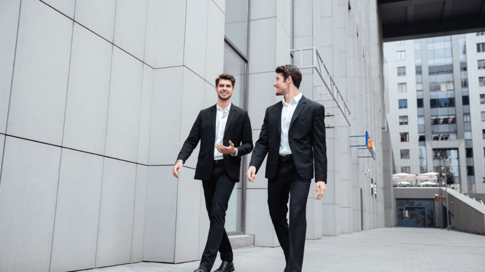 two-businessmen-walking-and-talking-in-the-city-PMW8E26