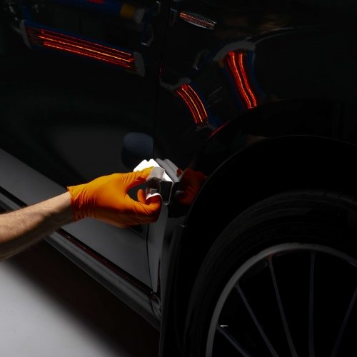 Car polish wax worker hands polishing car. Buffing and polishing vehicle with ceramic. Car detailing. Man holds a polisher in the hand and polishes the car with nano ceramic. Tools for polishing