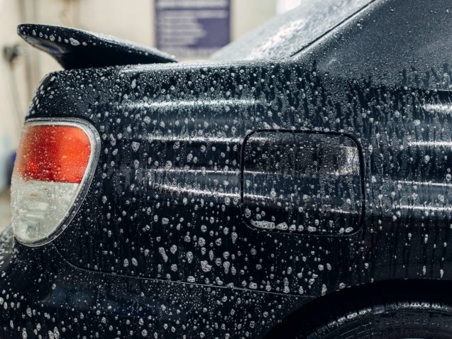 Carwash service, car in foam, side view. Auto detailing, high pressure contactless washing on special station