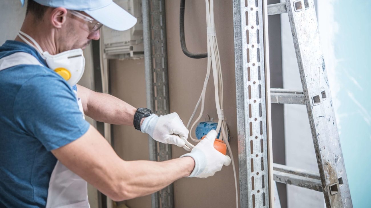 Electrical Installation Design. Caucasian Electrician Installing Electric Outlet in the Residential Construction.