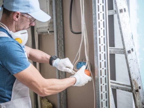 Electrical Installation Design. Caucasian Electrician Installing Electric Outlet in the Residential Construction.