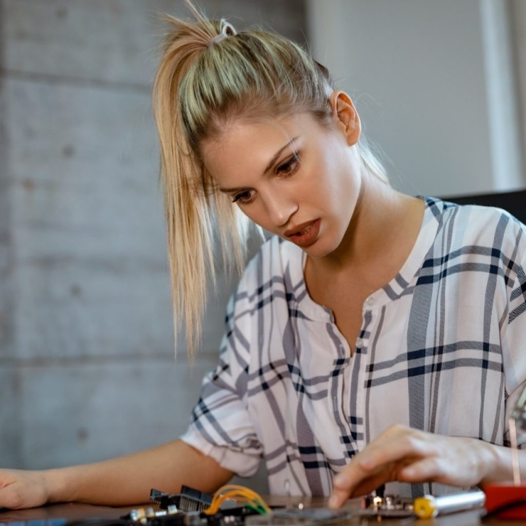 woman-testing-circuit-board-in-her-office-8WM2R6N-croped