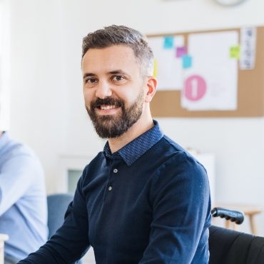 young-businessman-in-wheelchair-with-colleagues-EWTN4AC
