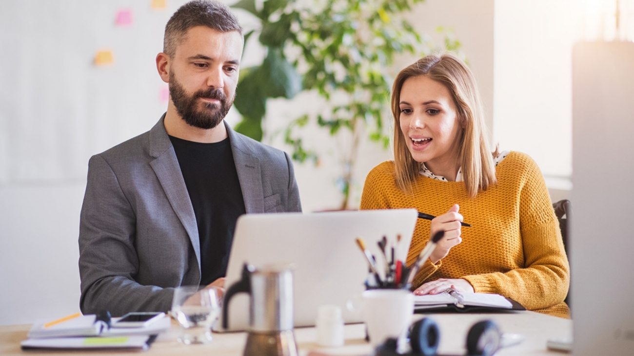 two-business-people-with-wheelchair-in-the-office-P7XLSBC