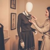 young-woman-looking-at-necklace-on-mannequin-in-PSQQMMH