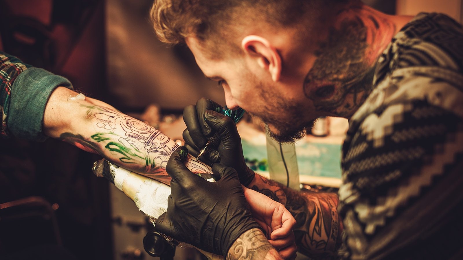 Tattoo artist makes a tattoo on a man's hand